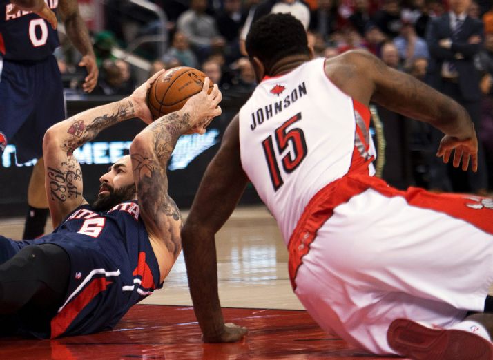 Toronto Raptors forward Amir Johnson (15) battles for the ball against Atlanta Hawks forward Pero Antic, left, during the first half of an NBA basketball game in Toronto on Sunday, March 23, 2014. (AP Photo/The Canadian Press, Nathan Denette)