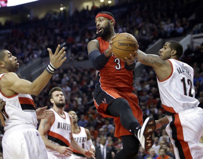 Toronto Raptors forward James Johnson, middle, looks to pass as Portland Trail Blazers' LaMarcus Aldridge, right, and Nicolas Batum, from France, defend during the first half of an NBA basketball game in Portland, Ore., Tuesday, Dec. 30, 2014.(AP Photo/Don Ryan)