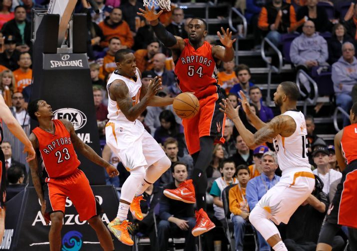 Phoenix Suns' Eric Bledsoe, center, dishes off to Marcus Morris (15) as Toronto Raptors' Patrick Patterson (54) and Lou Williams (23) defend during the first half of an NBA basketball game, Sunday, Jan. 4, 2015, in Phoenix. (AP Photo/Matt York)