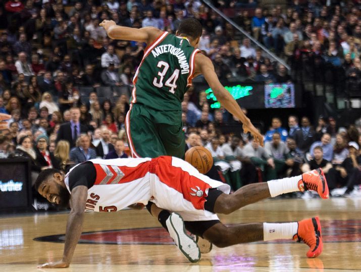 Toronto Raptors forward Amir Johnson, front, trips up Milwaukee Bucks forward Giannis Antetokounmpo (34) during the first half of an NBA basketball game in Toronto, Monday, Feb. 2, 2015. (AP Photo/The Canadian Press, Nathan Denette)